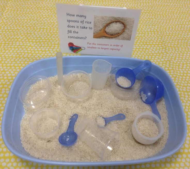 a blue bowl filled with white sand and measuring spoons on top of a table