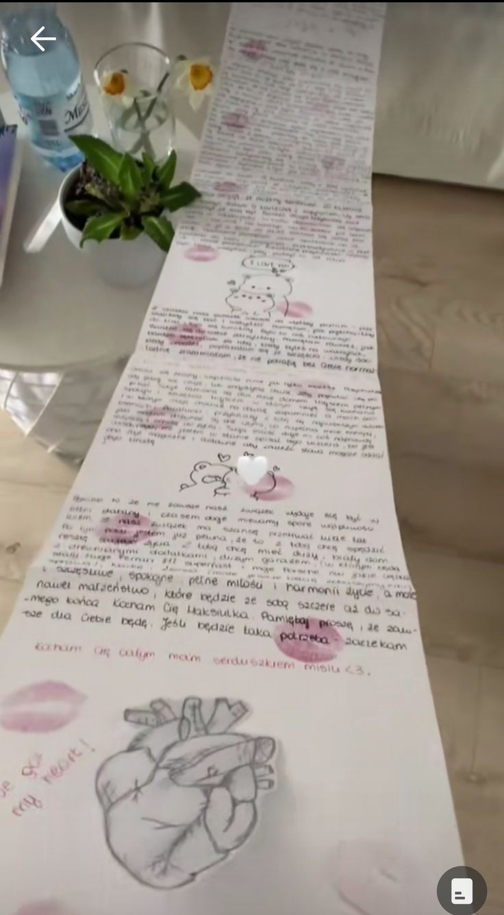 a table runner with writing on it and flowers in vases behind the runner is a drawing of a human heart