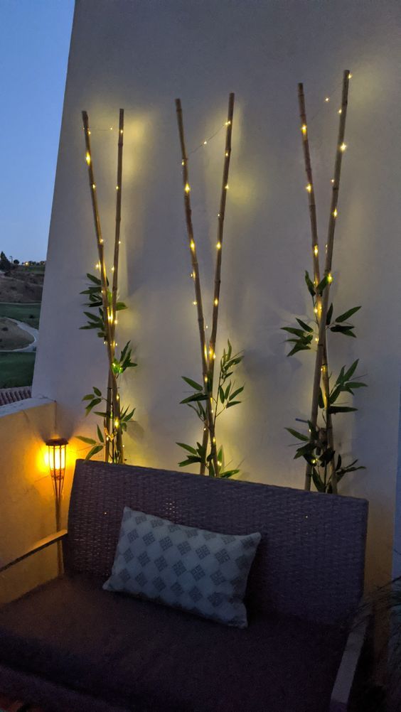 some lights are hanging on the side of a wall next to a couch with pillows