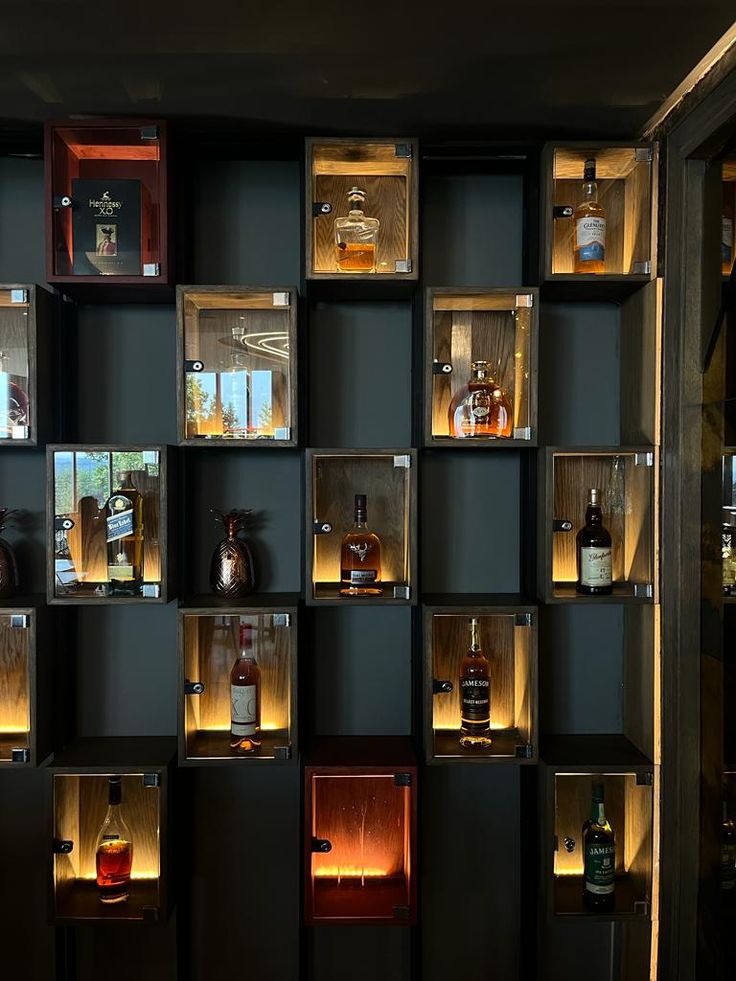 shelves filled with bottles and lit candles in the dark room for liquors to be consumed