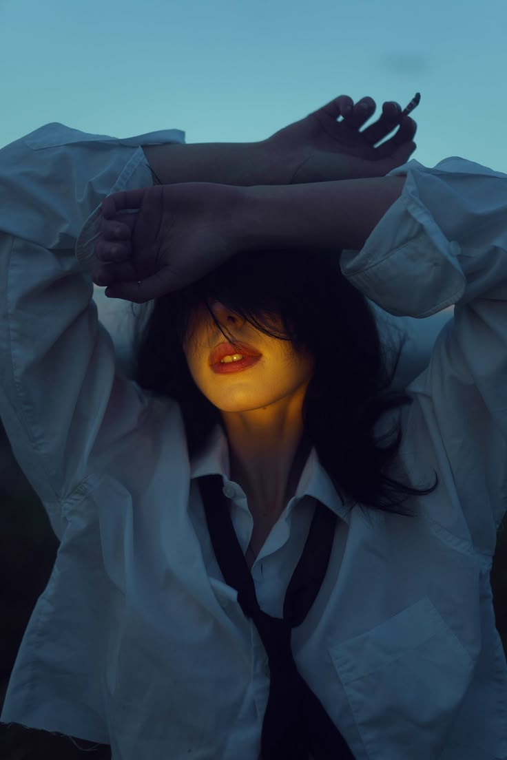 a woman in white shirt and black tie holding her hands up to her head with glowing eyes