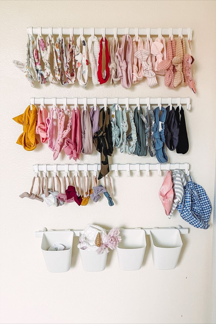 a wall mounted rack with baby clothes hanging from it's sides and two white buckets on the side