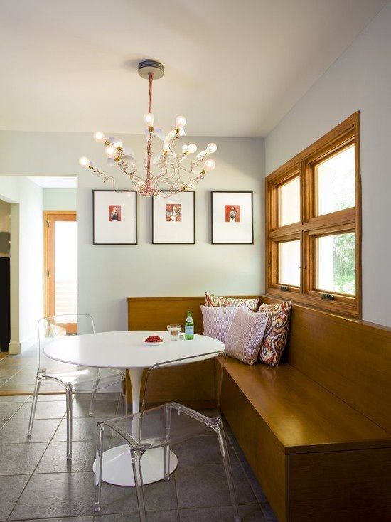 a dining room table and bench with pictures on the wall behind it in front of a window