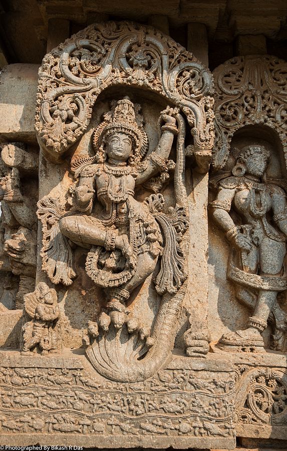 an intricately carved sculpture on the side of a building, depicting deities and animals