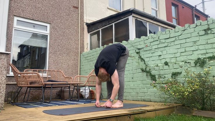 a man bending over on top of a mat in front of a brick wall and patio