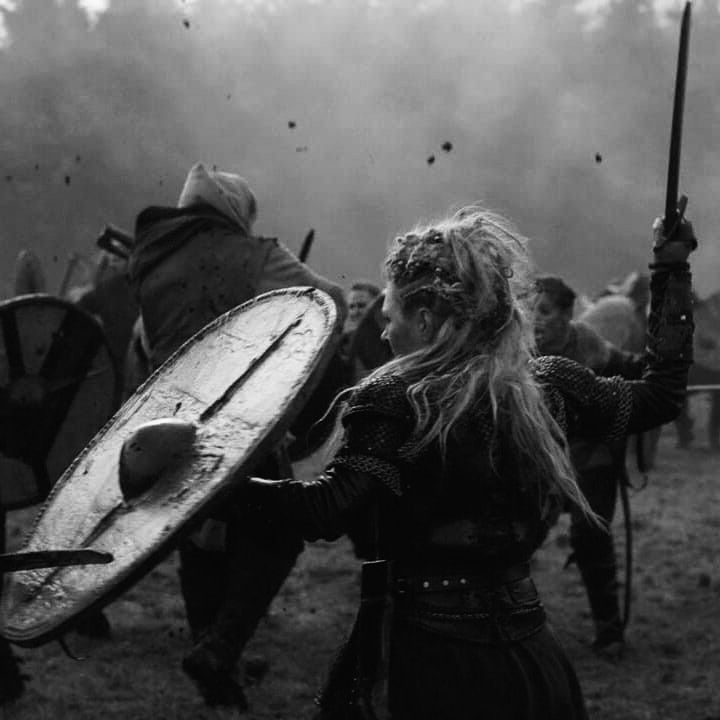 a black and white photo of people dressed in medieval costumes holding swords, shields and shieldes