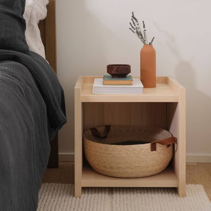 a bed room with a neatly made bed and a vase on the nightstand next to it