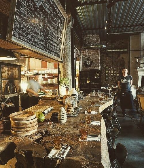 a person standing in front of a table with food on it and menus hanging from the ceiling