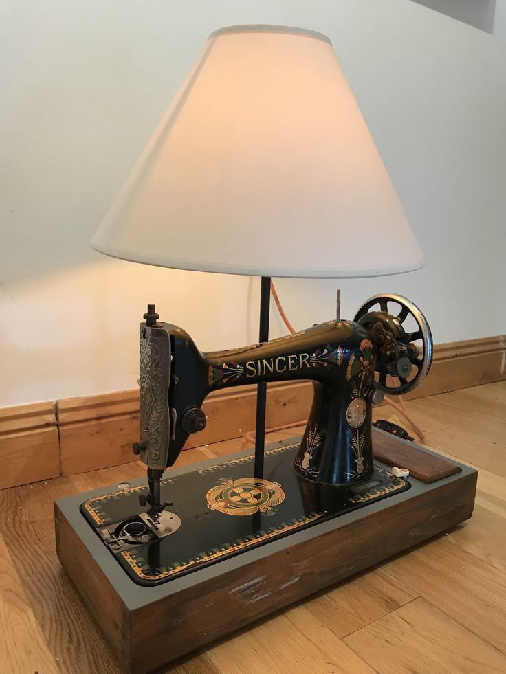 an old sewing machine is sitting on a wooden table with a lamp in front of it