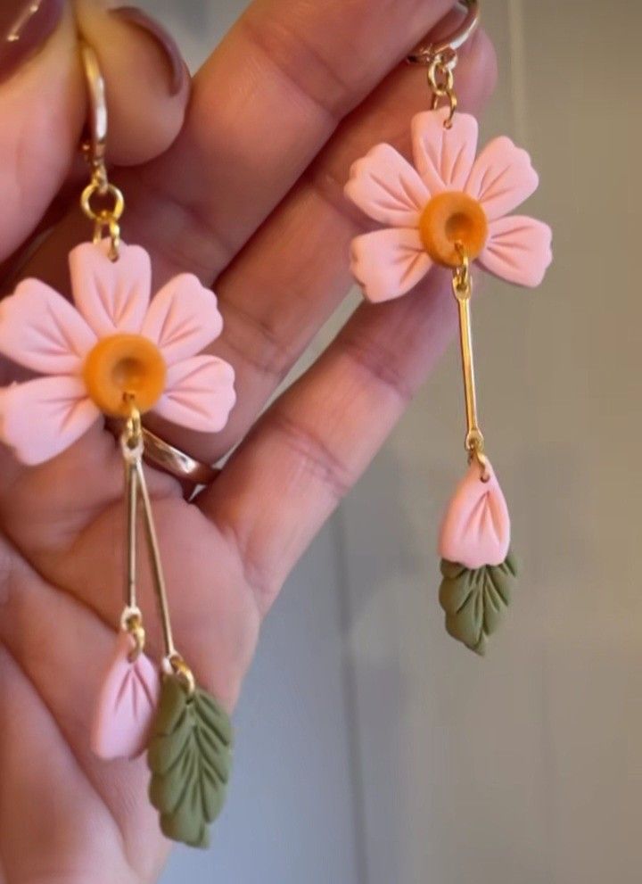 a pair of pink and green flower dangle earrings with leaves on the end, hanging from gold - plated earwires