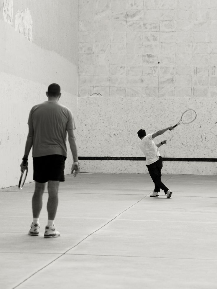 a man holding a tennis racquet while standing next to another man on a court