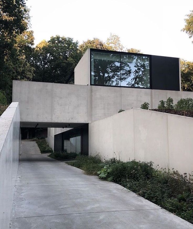 a concrete building with plants growing on the side and an overpass leading up to it