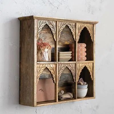 a wooden shelf with several different items on it and a white wall in the background