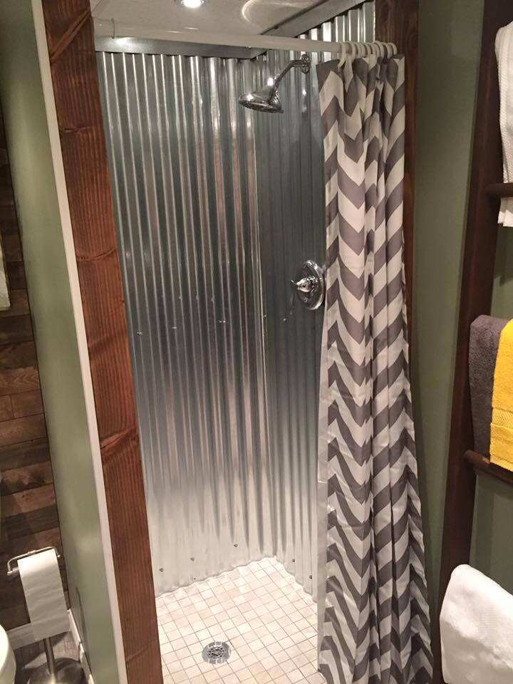 a bathroom with a shower, toilet and sink in it's stall door is open