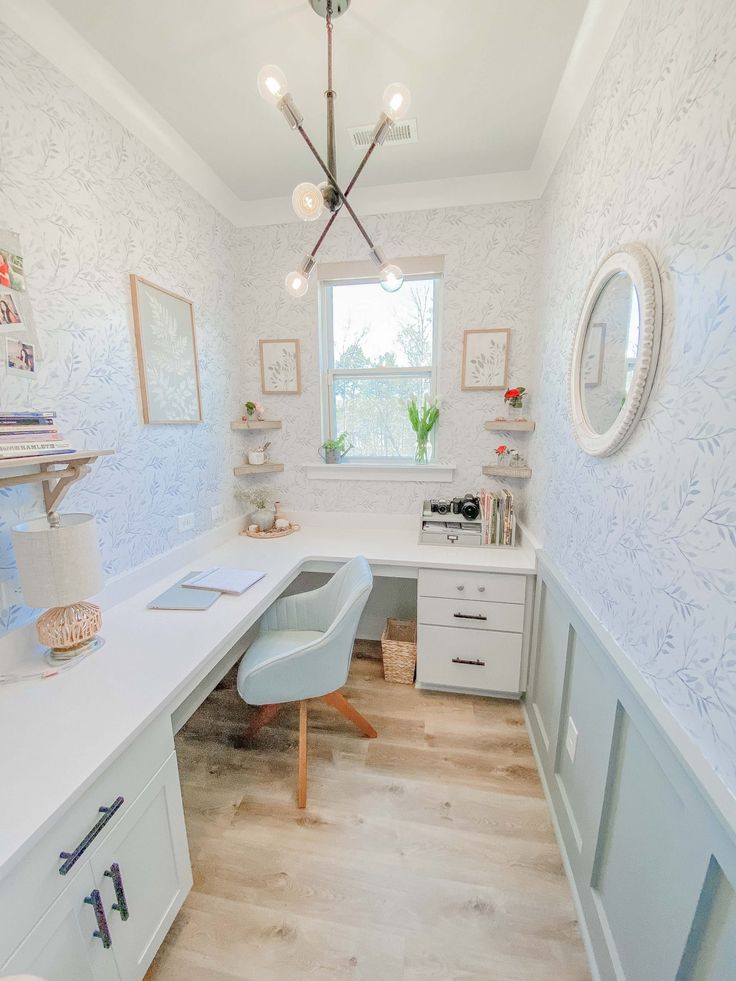 a home office with white desks and blue wallpaper on the walls, along with wooden flooring