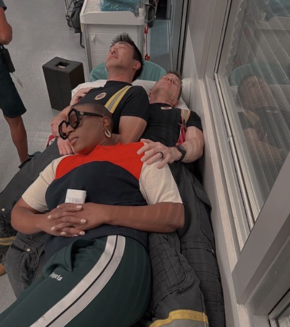 three people are sleeping on the floor next to an open window and one person is wearing glasses