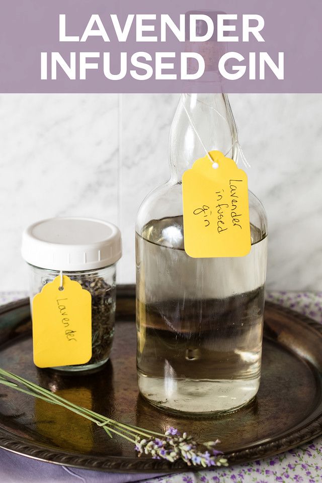 lavender infused gin in a glass bottle with two tags attached to it and on a tray