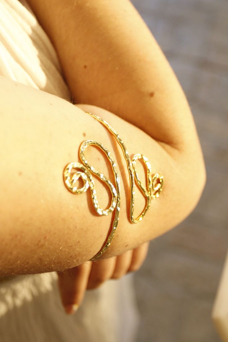 a close up of a person wearing a gold bracelet with the letter s on it