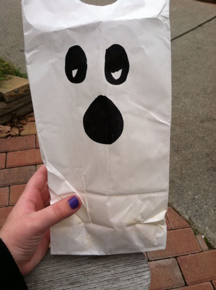 a hand holding a paper bag with a face on it