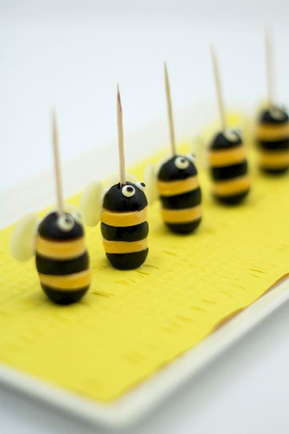 there are many small black and yellow candies on the plate with toothpicks in them