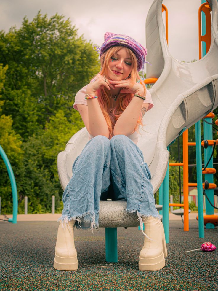 a woman sitting on top of a slide at a playground