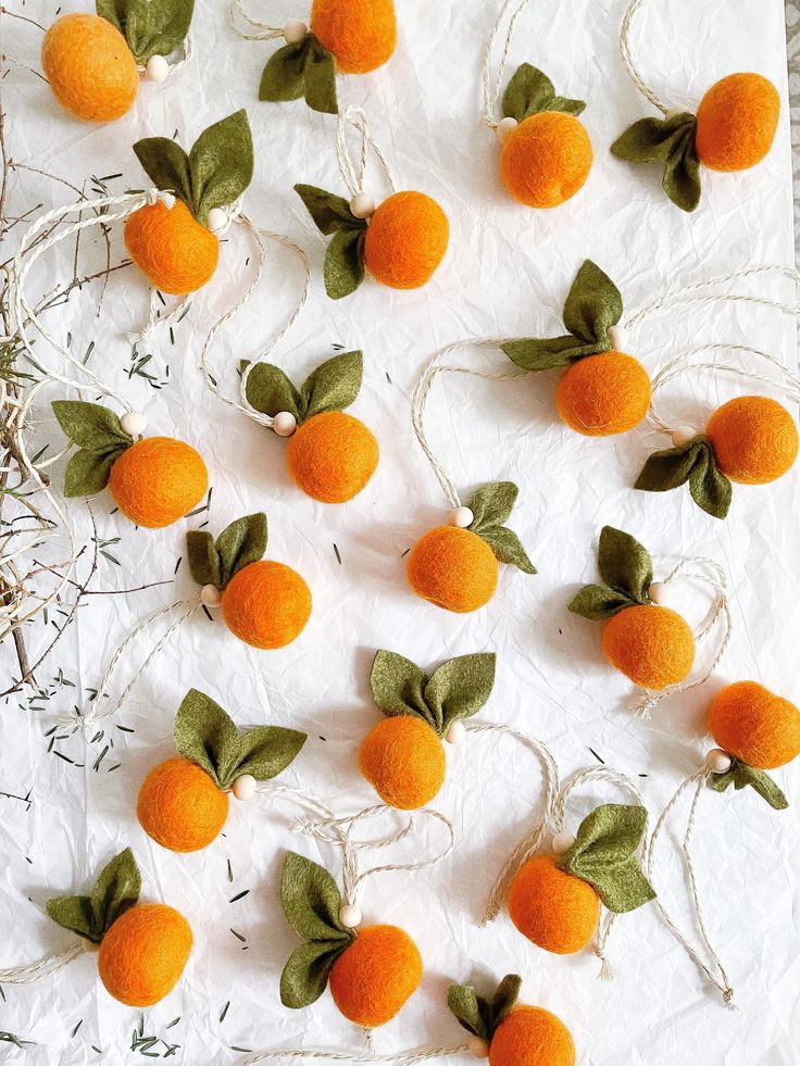 small oranges with green leaves and twine on white paper