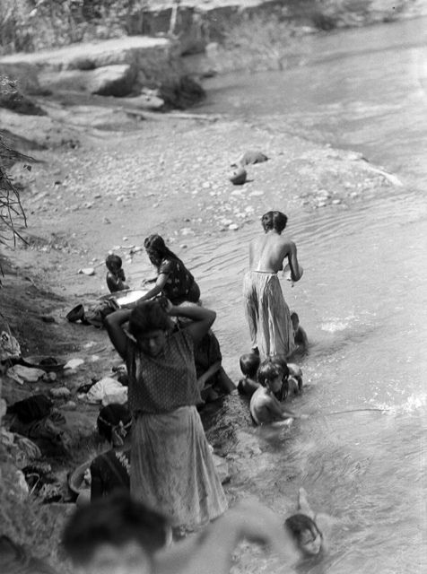 some people are standing in the water and one is holding a baby while others look on