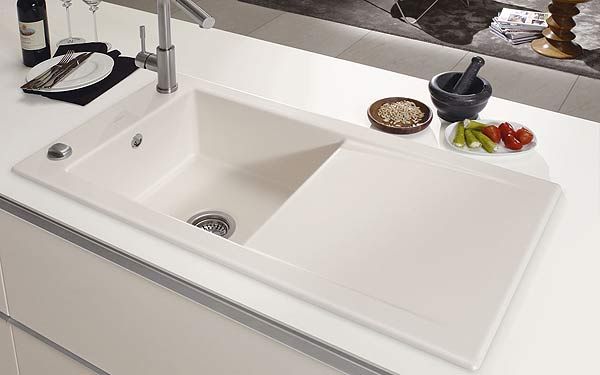 a white kitchen sink sitting on top of a counter next to a wine glass holder