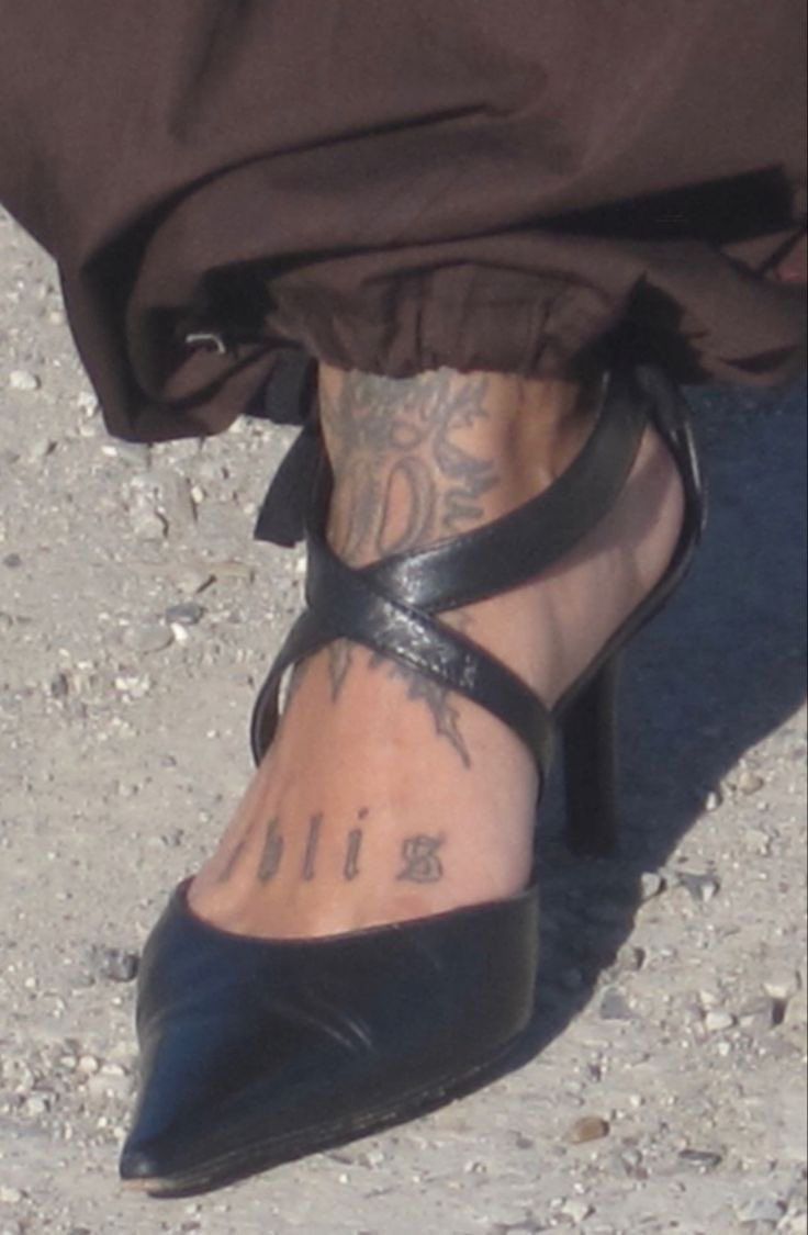 a person with tattoos on their feet wearing black shoes