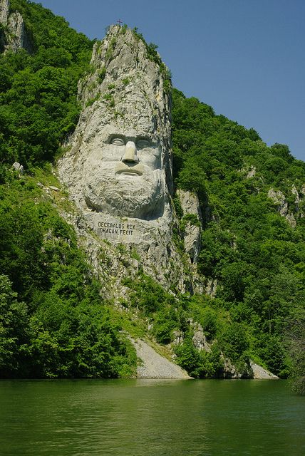 there is a large face carved into the side of a mountain next to a lake