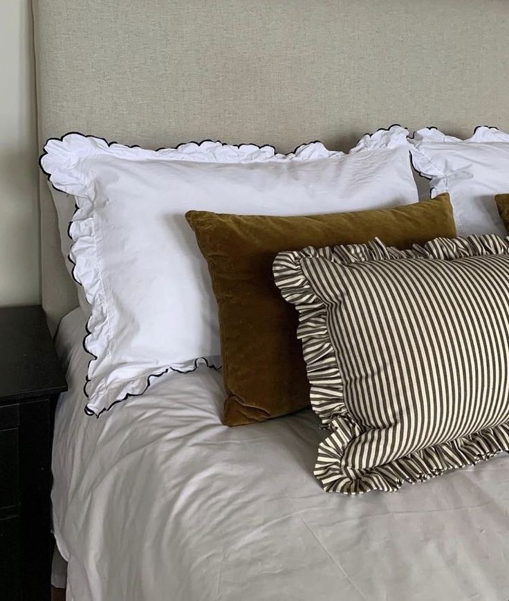 a bed with white sheets and brown pillows