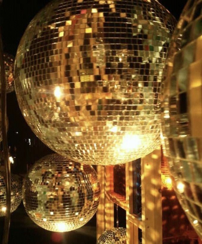 disco balls are hanging from the ceiling in front of a mirror ball sculpture at night