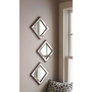 three mirrors mounted to the side of a wall next to a pillow on a window sill