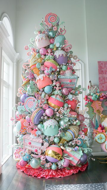 a decorated christmas tree in the corner of a room with pink and green ornaments on it