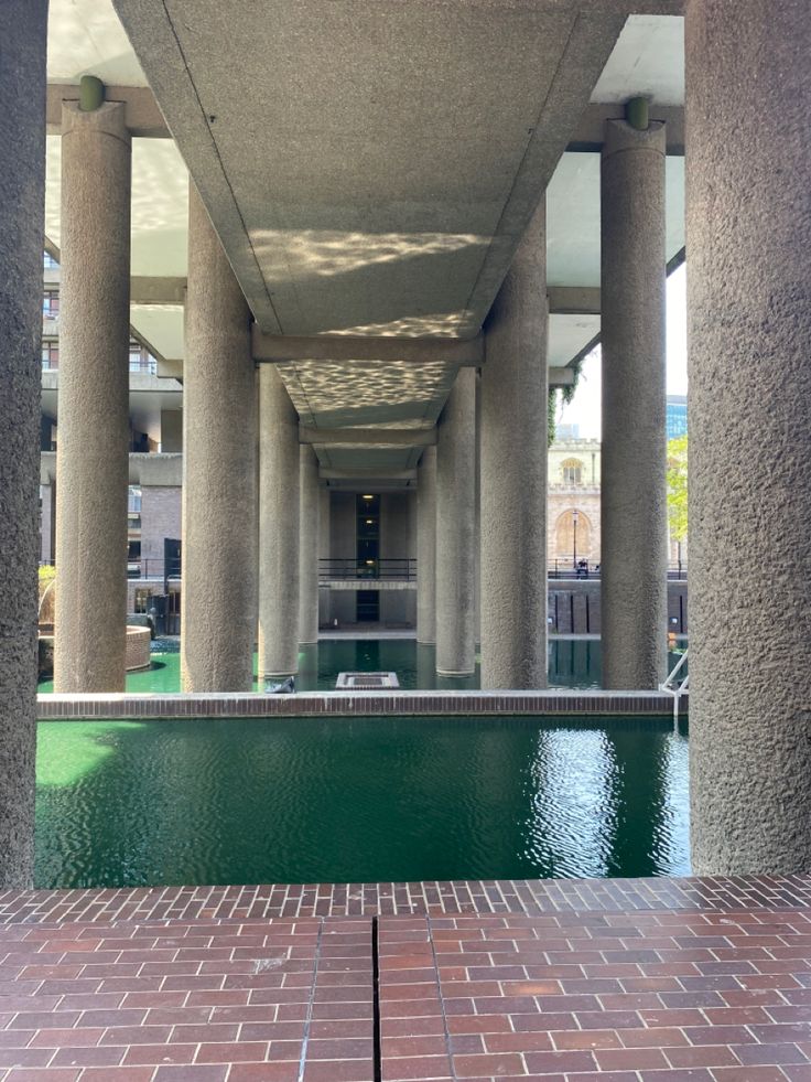 an empty swimming pool in the middle of a building with large pillars and columns on either side