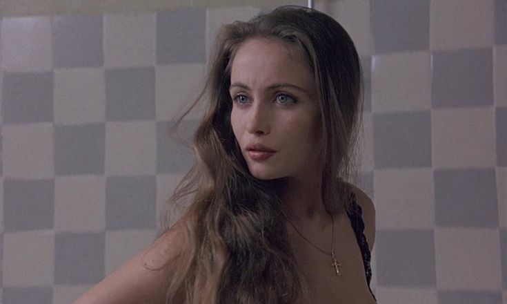 a woman with long hair standing in front of a tiled wall