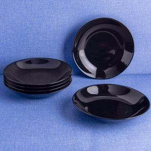 four black plates on a blue cloth with one empty plate in the middle and two empty ones