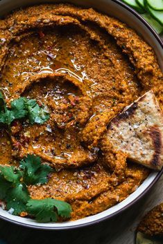 a bowl filled with hummus, pita bread and cilantro on top