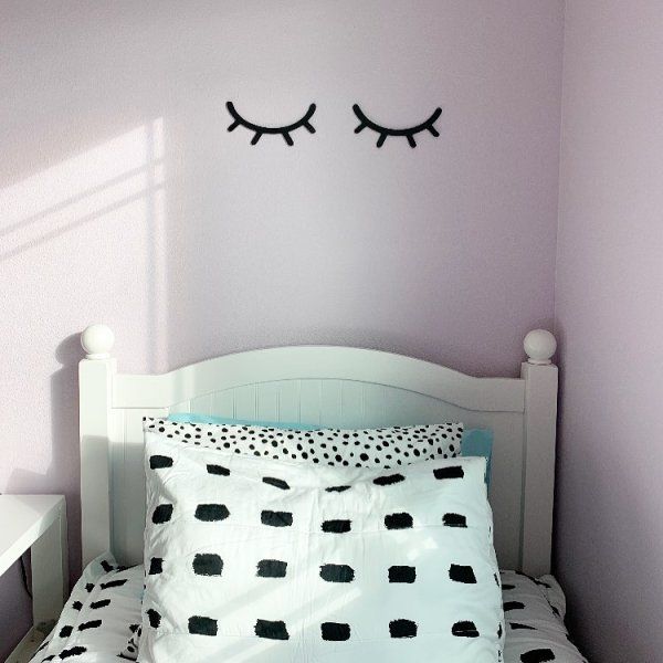 a white bed topped with two pillows next to a wall painted in black and white