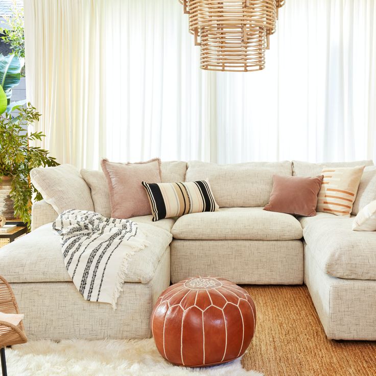 a living room filled with lots of furniture and pillows on top of a white rug