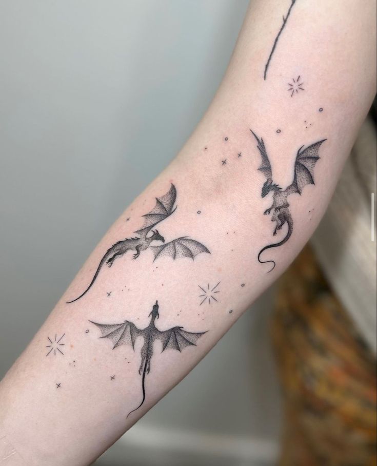 a woman's arm with three flying dragon tattoos on the left side of her arm