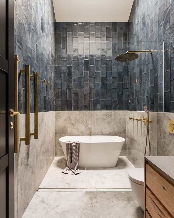 a bathroom with blue tiles and a white bathtub in the center, along with wooden cabinets