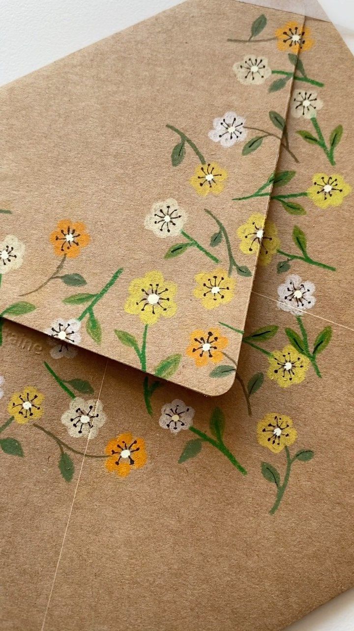 two envelopes with flowers painted on them, one is open and the other closed