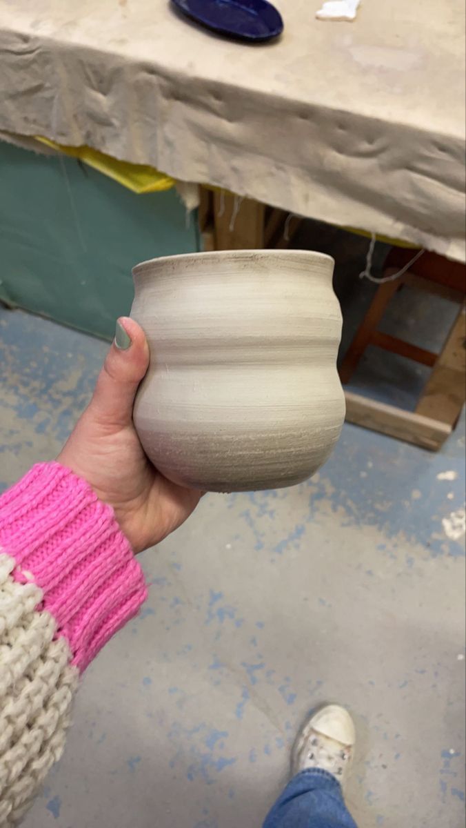 a person holding a white vase in their hand