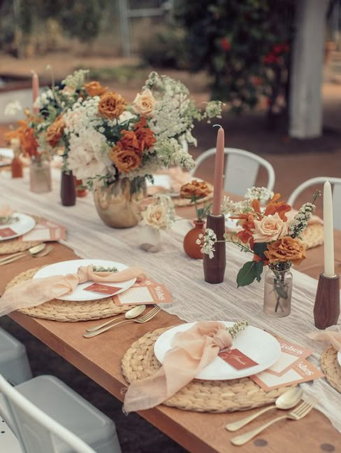 an outdoor table set with place settings and flowers