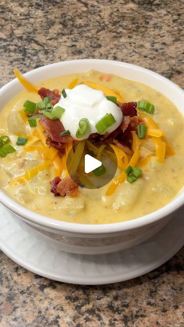 a white bowl filled with soup topped with sour cream and green onions on top of a marble counter