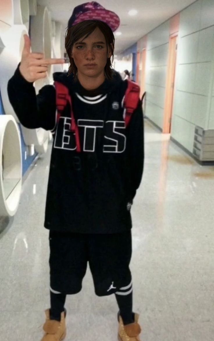 a young man is standing in the hallway with his hand up and wearing a hat