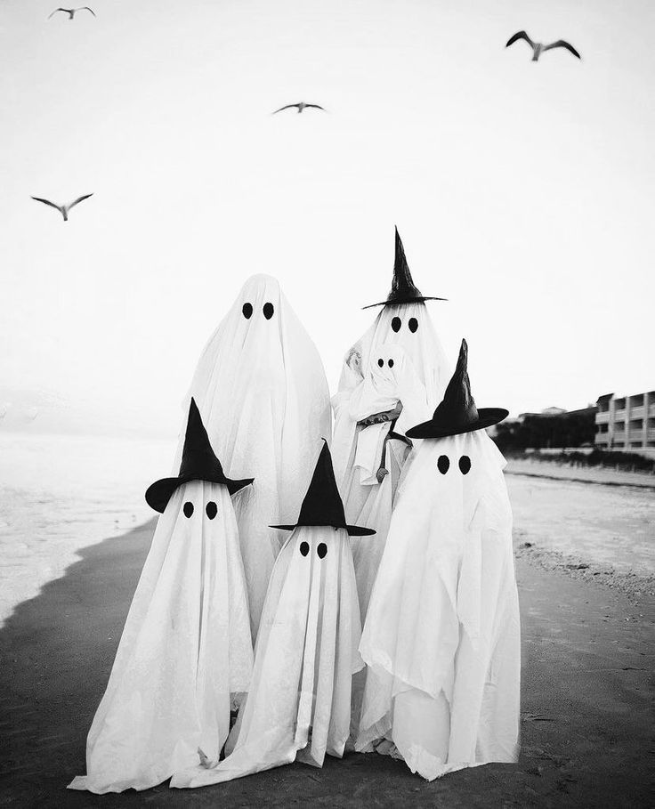 black and white photograph of three ghostly figures on beach with seagulls in background