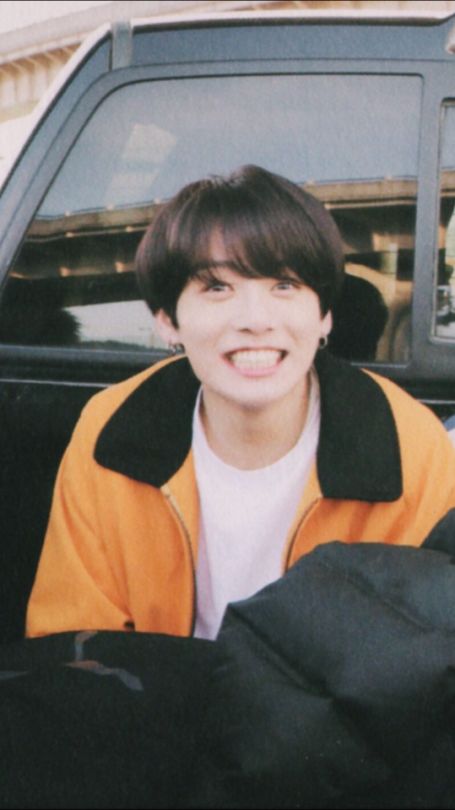 a young man sitting in the back of a pick up truck smiling at the camera