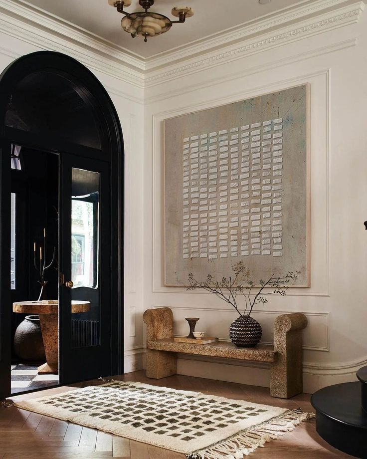 a living room filled with furniture and a large painting on the wall above it's doorway